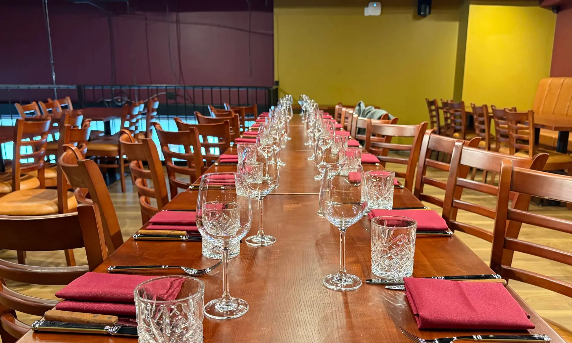 A long table set with wine glasses and red napkins